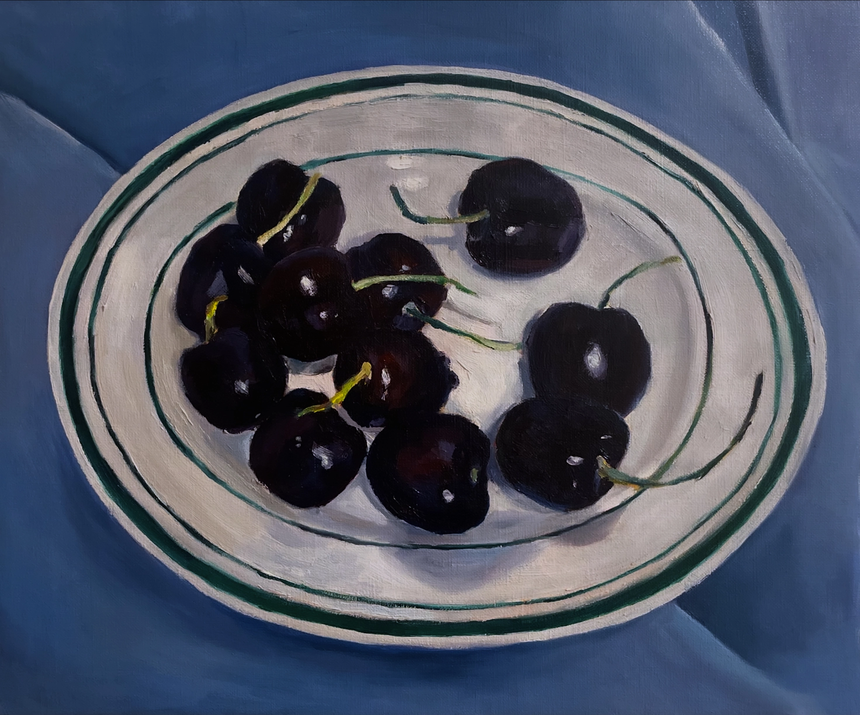 複数のさくらんぼが白いお皿に載せられ、青い色味の布の上に置かれている情景が油絵具で描かれた絵画